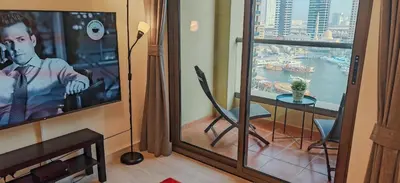 a living room with a tv and a table and a view at La Buena Vida Holiday Homes, Luxe, 3BR with, full kitchen, Marina View, by JBR Beach, Tram & Marina in Dubai