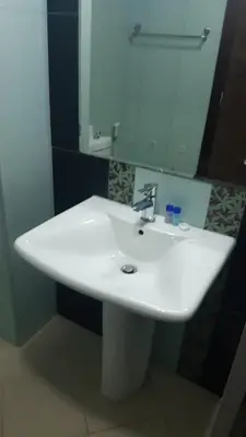 a white sink in a bathroom with a mirror at Vacay Lettings - Silicon Oasis Budget Friendly Studio in Dubai