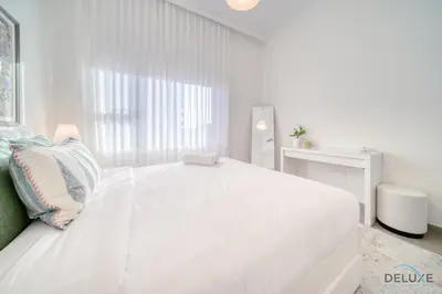 a white bedroom with a large white bed and a window at Graceful 1BR at Park Heights Dubai Hills MBR City by Deluxe Holiday Homes in Dubai