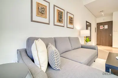a living room with a gray couch with pillows at Graceful 1BR at Park Heights Dubai Hills MBR City by Deluxe Holiday Homes in Dubai