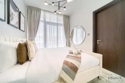 a bedroom with a white bed and a mirror at Cheerful 3BR Townhouse at DAMAC Hills 2, Dubailand by Deluxe Holiday Homes in Dubai
