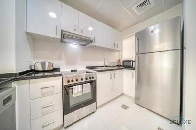 a kitchen with white cabinets and a stainless steel refrigerator at Cheerful 3BR Townhouse at DAMAC Hills 2, Dubailand by Deluxe Holiday Homes in Dubai