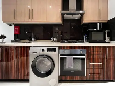 a kitchen with a washing machine and a microwave at Trophy Stays - Supreme Sunrise Suites w Burj Khalifa view - Studio in Dubai