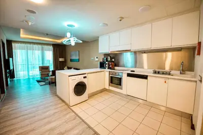 a kitchen with white cabinets and a washer and dryer at FAHH - Superior 1BHK Address Dubai Mall Residences in Dubai
