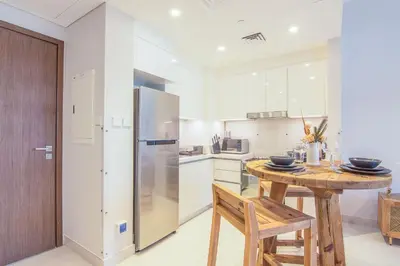 a kitchen with a wooden table and a refrigerator at Brand new 1 bedroom apartment Dubai Hills 601 in Dubai