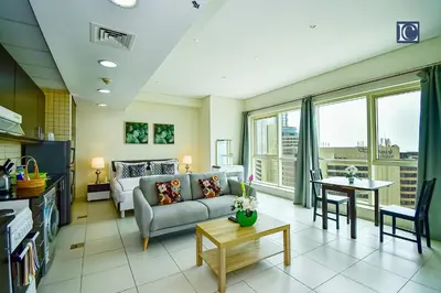 a living room with a couch and a table at Luxury Escapes - Furnished studio with balcony in Royal Oceanic in Dubai