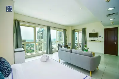 a living room with a couch and large windows at Luxury Escapes - Furnished studio with balcony in Royal Oceanic in Dubai