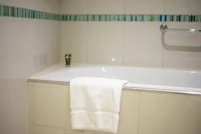 a white bathroom with a tub and a towel at Blue dream apartment with Harbour view in Marina in Dubai
