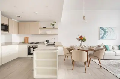 a white kitchen with a table and a couch at Frank Porter - Belgravia 3 in Dubai