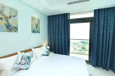 a bedroom with a bed with blue curtains and a window at Paramount Midtown - Fantastic 2 Bedroom Apartment with Sea View in Dubai