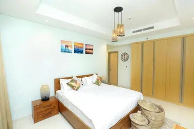a bedroom with a white bed and a wooden cabinet at Paramount Midtown - Fantastic 2 Bedroom Apartment with Sea View in Dubai