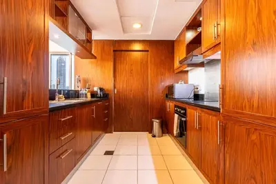 a kitchen with wooden cabinets and a tile floor at Splendid 3BR Apartments - Burj Khalifa & Fountain Views - 5 Minutes Walk from Dubai Mall in Dubai