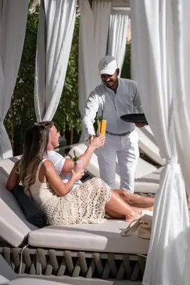 a man holding a drink and a woman on a bed at Wyndham Residences The Palm in Dubai