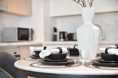 a table with plates and a vase on top of it at The Smart Concierge - Beach Vista 2 in Dubai