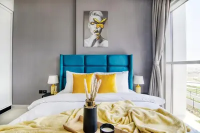 a bedroom with a blue headboard and yellow pillows at GuestReady - In the Heart of Dubai Hills in Dubai