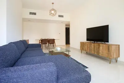a living room with a blue couch and a flat screen tv at AG Tower - 1BR Apartment - Allsopp&Allsopp in Dubai