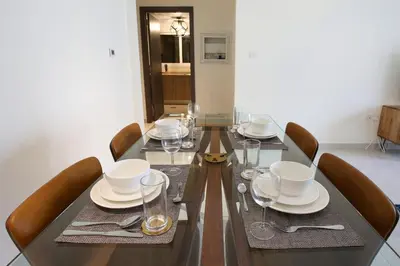 a dining table with chairs and plates and wine glasses at AG Tower - 1BR Apartment - Allsopp&Allsopp in Dubai