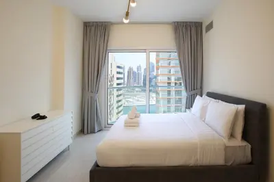 a bedroom with a bed and a large window at AG Tower - 1BR Apartment - Allsopp&Allsopp in Dubai