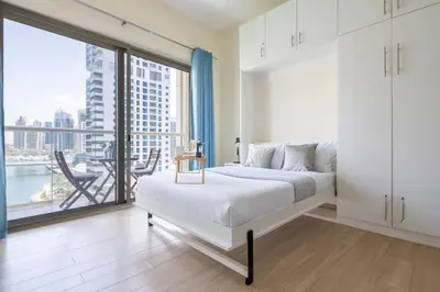 a white bedroom with a bed and a large window at Frank Porter - Marina Views B in Dubai