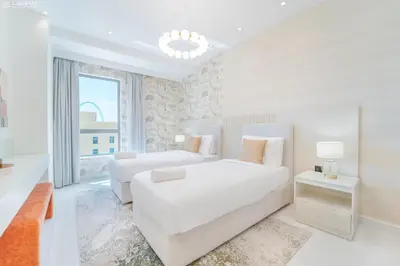 a white bedroom with two beds and a couch at JBR Amwaj 4 , Upgraded Sea and Ain Dubai Views, 2m walk to Beach By Gardenia Suitse in Dubai