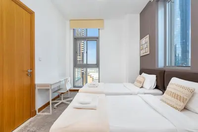 two beds in a room with a desk and windows at Vacay Lettings - 2BHK with Dubai Marina View in Dubai