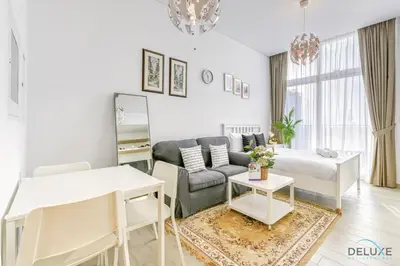 a living room with a couch and a table at Cheerful Studio at Belgravia Tower JVC by Deluxe Holiday homes in Dubai