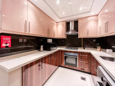 a kitchen with wooden cabinets and a sink at Luton Vacation Homes - Elite Downtown Residence, Burj Khalifa View Dubai - 19AB01 in Dubai