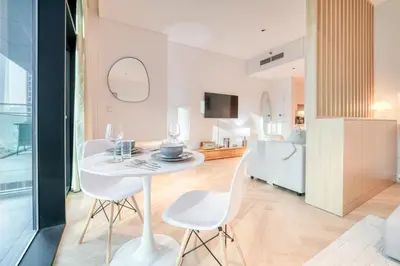 a dining room and kitchen with a white table and chairs at Luxury Studios with Burj Khalifa View or Canal view - Marquise Square Tower in Dubai