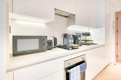 a kitchen with white cabinets and a microwave at Luxury Studios with Burj Khalifa View or Canal view - Marquise Square Tower in Dubai
