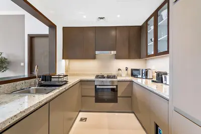 a large kitchen with wooden cabinets and a sink at Silkhaus modern Boulevard 1BDR near Burj Khalifa in Downtown in Dubai
