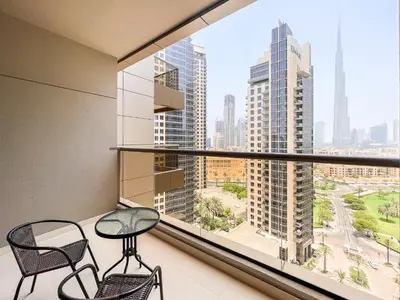 a balcony with two chairs and a large window at Luton Vacation Homes - Elite Downtown Residence Studio, Burj Khalifa View Dubai - 80AB3 in Dubai