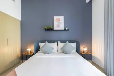 a bedroom with a large bed with a blue wall at Daniels 1BR at Creek Horizon with Park View in Dubai