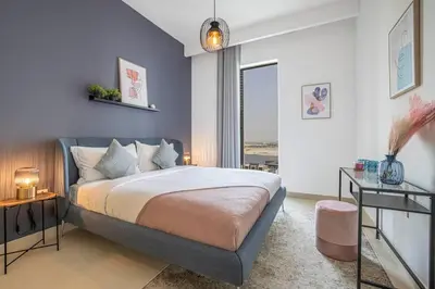 a bedroom with a large bed and a blue wall at Daniels 1BR at Creek Horizon with Park View in Dubai