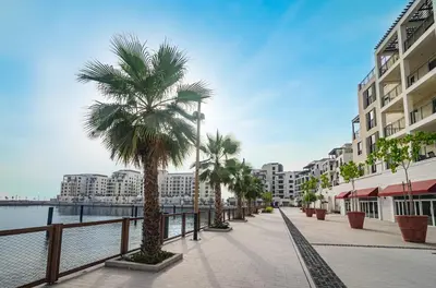 a street with palm trees and buildings next to the water at Outstanding New Apartment with Sea View In La Mer in Dubai