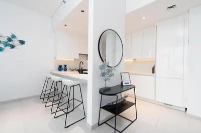 a kitchen with white cabinets and a mirror and stools at Ultimate Stay / 4 Beds / Burj Khalifa View / Ultra Modern / Business Bay in Dubai