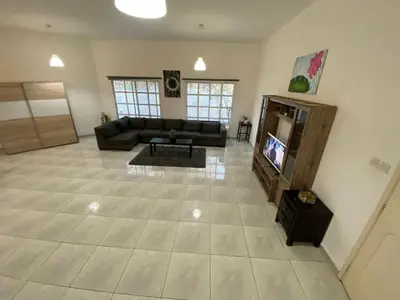 a living room with a couch and a tv at Comfortable Private Rooms in Compound Housing in Dubai