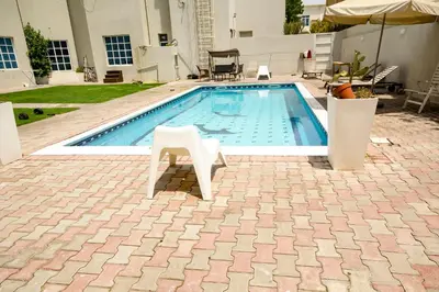 a swimming pool with a white chair sitting next to it at Comfortable Private Rooms in Compound Housing in Dubai