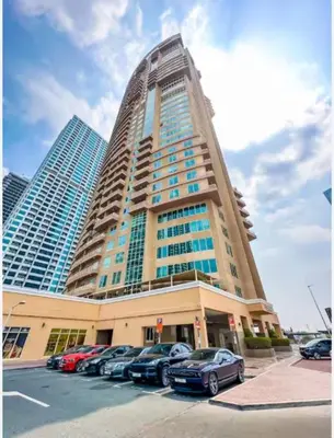 a large building with cars parked in a parking lot at HomesGetaway -Fanciful 1BR Apartment in JLT Lake View in Dubai