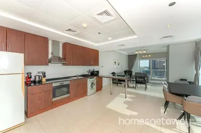 a kitchen with a refrigerator and a table with chairs at HomesGetaway -Fanciful 1BR Apartment in JLT Lake View in Dubai