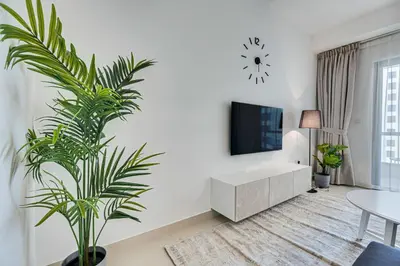 a white living room with a tv and a plant at 2 BD apartment in Bahar JBR in Dubai