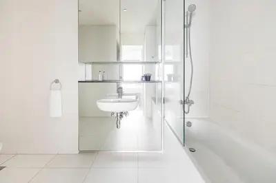 a white bathroom with a sink and a shower at Frank Porter - Index Tower in Dubai