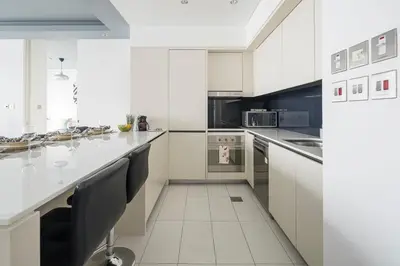 a white kitchen with a large white counter top at Frank Porter - Index Tower in Dubai