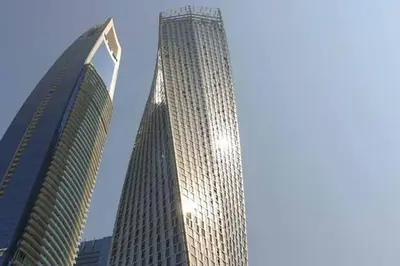a tall skyscraper with the sun shining on it at Cayan old in Dubai