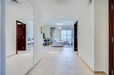 a hallway with white walls and tile floors and doors at 2BD apartment in Bahar JBR near beach in Dubai