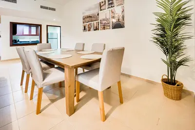 a dining room table with chairs and a potted plant at 2BD apartment in Bahar JBR near beach in Dubai