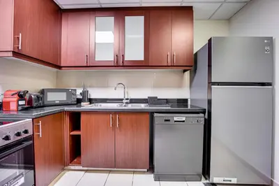 a kitchen with wooden cabinets and a stainless steel refrigerator at 2BD apartment in Bahar JBR near beach in Dubai