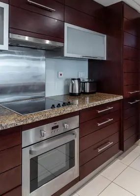 a kitchen with wooden cabinets and a stainless steel oven at Studio in Burj Views by Radiance Vacation Stays in Dubai