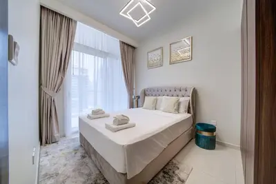 a bedroom with a bed with white sheets and a window at Classic Arabian Elegance with City Views in Dubai