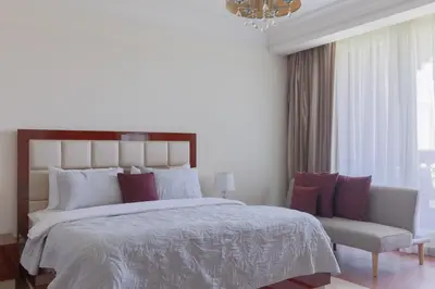 a bedroom with a large bed and a chair at 1-bedroom apartment with pool in Dubai
