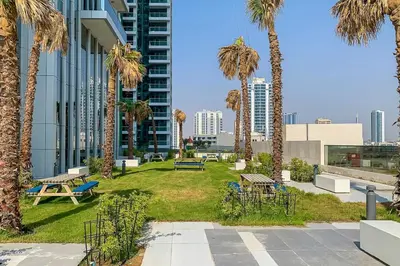 a park with benches and palm trees in a city at Frank Porter - Regina Tower in Dubai